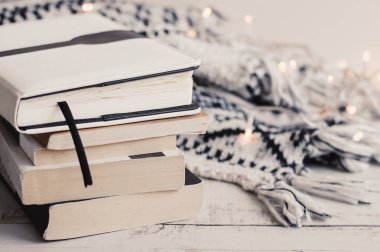 Kitap, ışıklar ve ahşap masa üzerinde sıcak örme battaniye. Ev dekorasyonu. Okuma kavramı