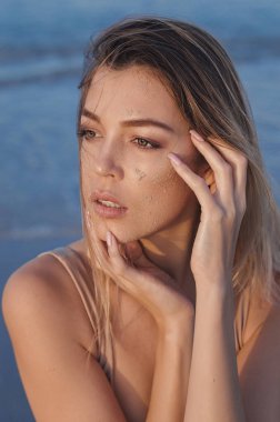 Plajda Yakalanan yüzünü dokunaklı bir kadın modeli portresi. Şehvetli bak. Kum ve ıslak saçlı, sahilde rahatlatıcı yüz