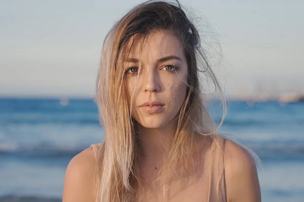 Horizontal portrait of a female with blond messy hair captured at the beach. Natural beauty concept