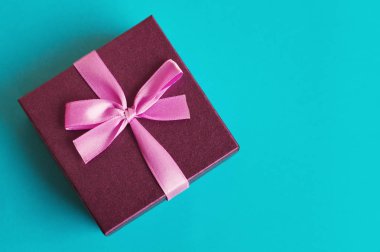Turkuaz renk arka planda pembe şerit ile küçük hediye kutusu. Doğum günü, yıldönümü, Noel, vb için mevcut.
