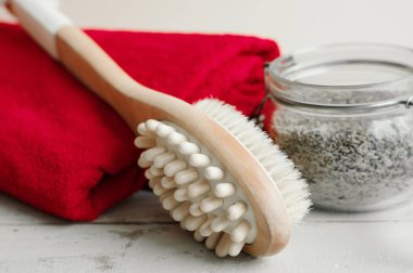 Vücut masajı için çok amaçlı fırça, ahşap arka plan üzerinde ev yapımı scrub ve kırmızı pamuklu havlu. Selülit tedavisi ve cilt peelingi