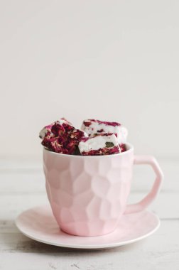 Yenilebilir çiçek yaprakları ile tatlı Türk Lokumu ile pembe kahve fincanı. Nuga