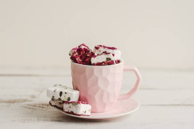 Ahşap masa üzerinde pembe bir kahve fincanı Hibiscus nougat. Türk lokumu. Lübnan tatlıları. Arap tatlısı