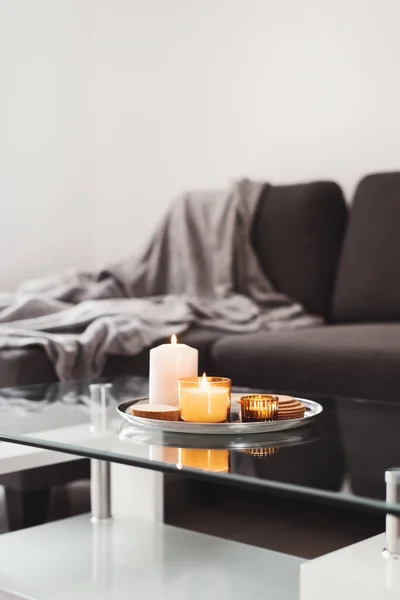 Basit bir oturma odası dekoru: metal tepside yanan aroma mumları olan kahve masası. Hygge konsepti. Asgari biçim