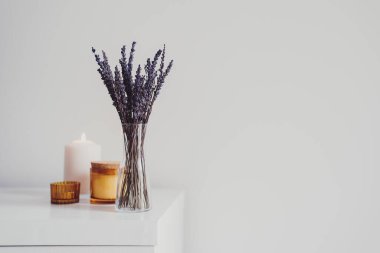 Küçük bir vazoda kurutulmuş lavanta ve aroma mumlarıyla kompozisyon. Asgari düzeyde. Ev dekoru. Aromaterapi ve spa konsepti. Oturma odası dekoru. Metin için boşluk