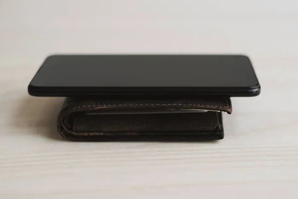 Black smart phone on top of the wallet. Mobile banking concept. Online or e-wallet concept