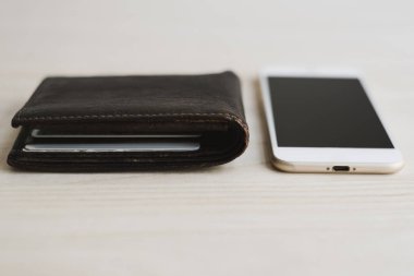 Kahverengi deri cüzdan ve cep telefonu ahşap masada. Çevrimiçi para kavramı. Taşınabilir aktarım ve bankacılık