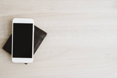 Deri cüzdan ve cep telefonu ahşap masa, üst görüş, kopyalama alanı. Mobil bankacılık. Bağlantısız para aktarım kavramı