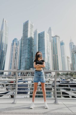 Kendine güveni tam genç bir kadın. Şehir caddesinde duruyor ve koruyucu yüz maskesi takıyor. Covid 19 veya Coronavirus koruması