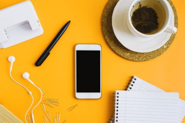 Yatay düzlük, akıllı telefon, yeşil çay ve sarı arka planda okul kırtasiyesi. Okul konseptine dönelim.