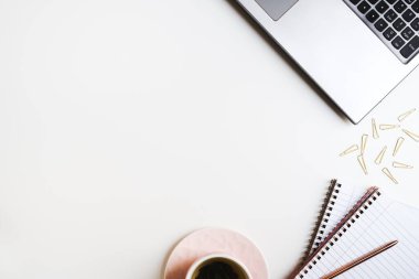 Bilgisayarı, ataçları, not defterleri ve bir fincan yeşil çayı olan temiz bir ofis masası. Kadınsı çalışma alanı düzlüğü