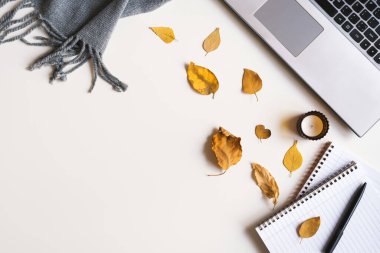 Bilgisayarı, mumu, defterleri, kalemi, battaniyesi ve küçük kurumuş yaprakları olan ofis masası. Sonbahar mevsimi düz yatıyordu