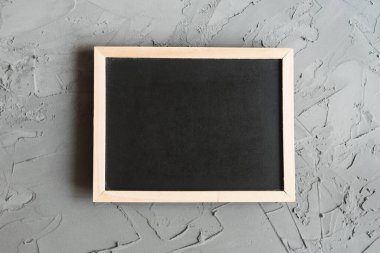 Beton arka planda ahşap çerçeveli küçük bir karatahta, üst manzara. Temiz tebeşir tahtası