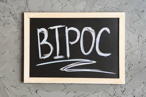 BIPOC kısaltması küçük bir karatahtaya yazılmış, arka plan olarak beton duvar. BIPOC siyah, yerli, renkli insanlar anlamına gelir