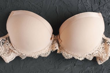 Beton arka planda bej sütyen. Kadın iç çamaşırları. Temel iç çamaşırı.