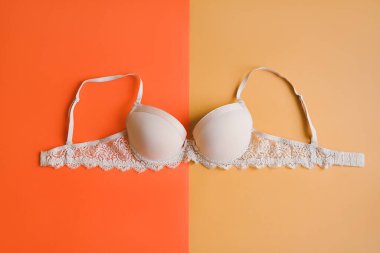 Turuncu ve sarı renkli parlak arkaplanda bej rengi sütyen, genel manzara. Kadın iç çamaşırı.