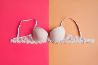 Pembe ve sarı arka planda bej sütyen, üst manzara. Kadın iç çamaşırı.