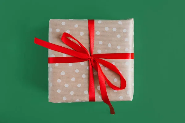 Рождественский Подарок Завернутый Бумагу Горошек Красной Лентой Зеленом Фоне Вид — стоковое фото