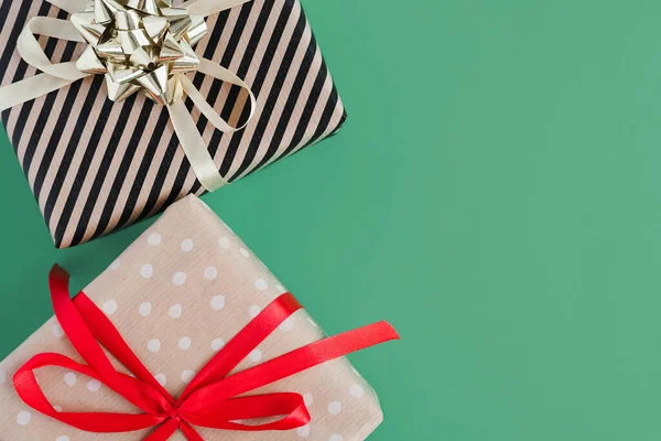 两个礼品盒用手工纸包着红色和黄色缎带 绿色背景 顶视图 复制空间 圣诞礼物 — 图库照片