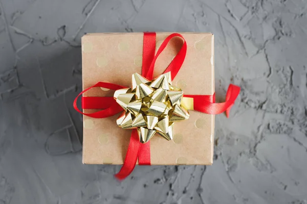 礼品盒 红色缎带 金色蝴蝶结 混凝土背景 顶视图 圣诞礼物 — 图库照片