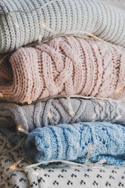 Sıcak örülmüş kazaklar ve dekoratif Noel ışıkları yığını. Soğuk mevsim için yün örgü.