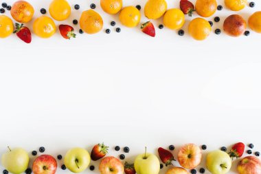 Yemek arkaplanı. Meyveler ve böğürtlenler beyaz masada, üst manzara, yazı için yer. Portakallar, elmalar, çilekler, yabanmersini deseni