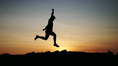 Kumsalda sırt çantalı bir adamın silueti.