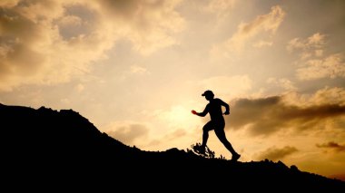 Kumsalda sırt çantalı bir adamın silueti.