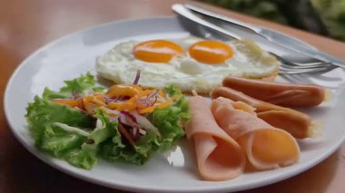 Yumurtalı kahvaltı, pastırma, sosis, salata, jambon ve sosis.