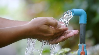 Açık havada akan bir musluğun altında ellerini yıkamak yeşillik, hijyen ve tazeliğin altını çizmek..