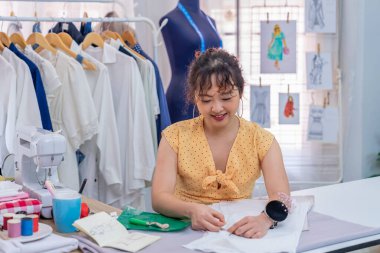 Genç bir kadın terzi atölyede yeni moda tasarım giysileri tasarlıyor.