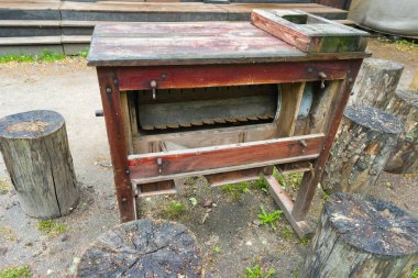 Eşsiz bir ekipman tasarımı olan eskimiş bir ahşap masa ağaç kütüklerinin yanında oturur. Doğal ortam yeşillik içeriyor, kırsal atmosferi geliştiriyor..