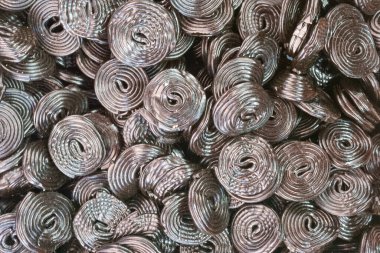 Renkli spiral şekerler canlı bir şekilde bir araya toplanır. Şekerler parlak yüzeyler ve karmaşık tasarımlar gösteriyor. Bu sahne büyük ihtimalle yerel bir marketten..