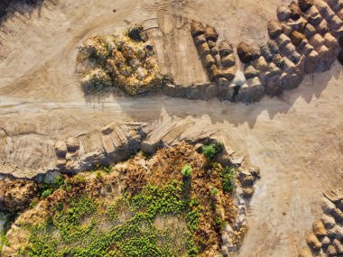 Ağır makineler toprağı taşıdı ve inşaat alanında toprak yığınları yarattı. Bir parça yeşil çimen, kahverengi toprakla çelişiyor. Bu da yakın zamandaki kara temizliğini gösteriyor..