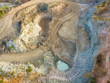 Hava manzarası, toprak yığınları, çamur yolları ve küçük su birikintileriyle büyük bir kazı alanı yakalar. Sahne, devam eden yeryüzü hareketlerini yansıtıyor..