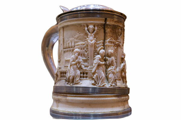 A beautifully crafted pitcher stands out with intricate carvings depicting historical scenes. The detailed artwork reflects cultural heritage and skilled artisanship from a bygone era.