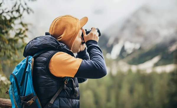 Çocuk ayna göl dağlarda, kahverengi bir ceket ve mavi bir sırt çantası içinde yürür