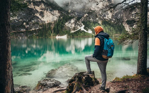 Çocuk ayna göl dağlarda, kahverengi bir ceket ve mavi bir sırt çantası içinde yürür