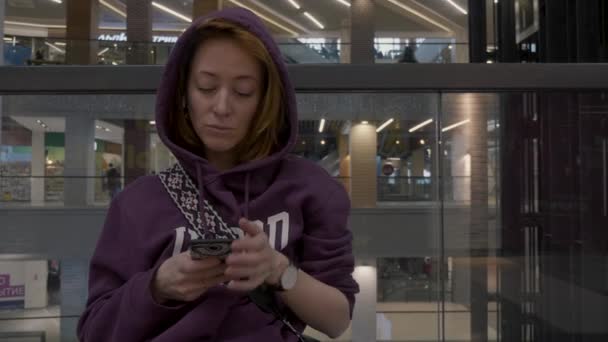 头发红头发的女孩坐在店里用手机 — 图库视频影像