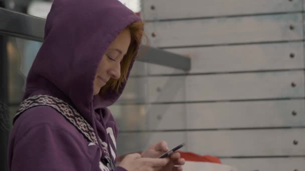 头发红头发的女孩坐在店里用手机 — 图库视频影像