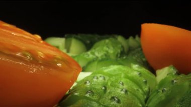 Kamera dilimlenmiş sebzelerin içinden geçiyor: salatalık ve domates, makro plan.