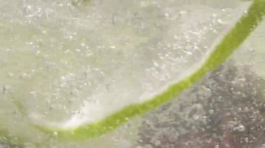 Bir bardak köpüklü suda bir dilim limon kıvrılır.