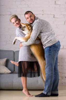 Güzel genç aile köpek ile stand hugs