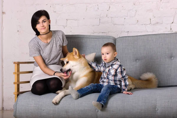 Beautiful mother and son with dog sits on sofa