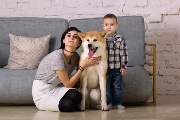 Beautiful mother and son with dog sits on floor