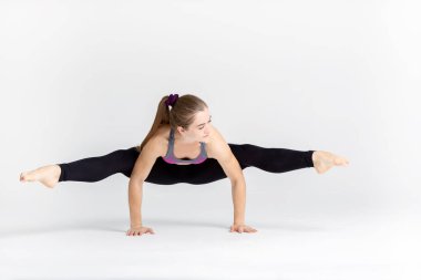 Beyaz arka plan üzerinde izole yerde otururken kas germe bir genç sportwoman tam uzunlukta portresi