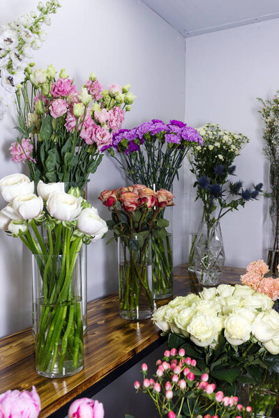 Красочные пионы, розы и другие цветы у входа в цветочный магазин. Селективный фокус
.