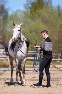 Genç adam yazın at ile manege 'de kordon üzerinde çalışıyor.