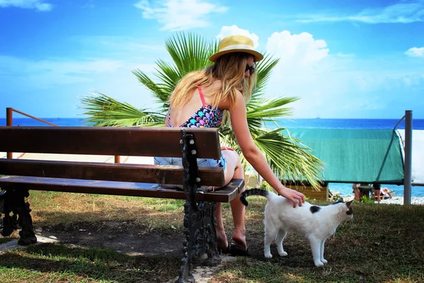 Giovane bella ragazza seduta e rilassarsi sulla panchina con gatto pigro bianco — Foto Stock