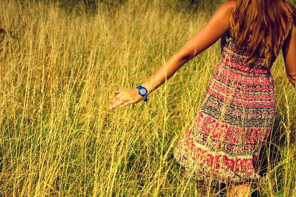 年轻漂亮的女孩在夏天走在通过高乾草的字段和运行的手 — 图库照片